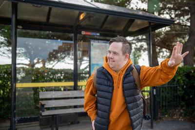 Photograph of person hailing a bus at a bus stop